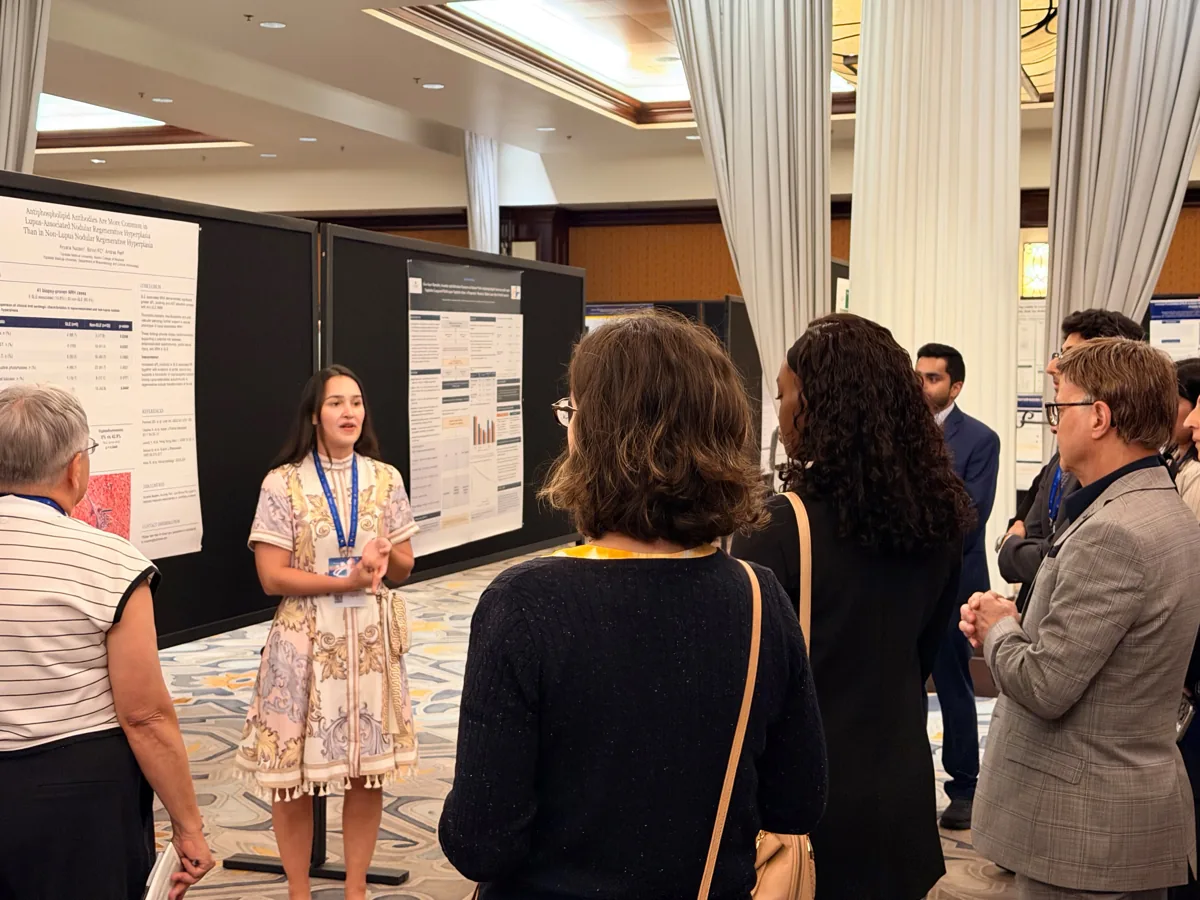 A presenter discussing her research with faculty and fellow investigators.