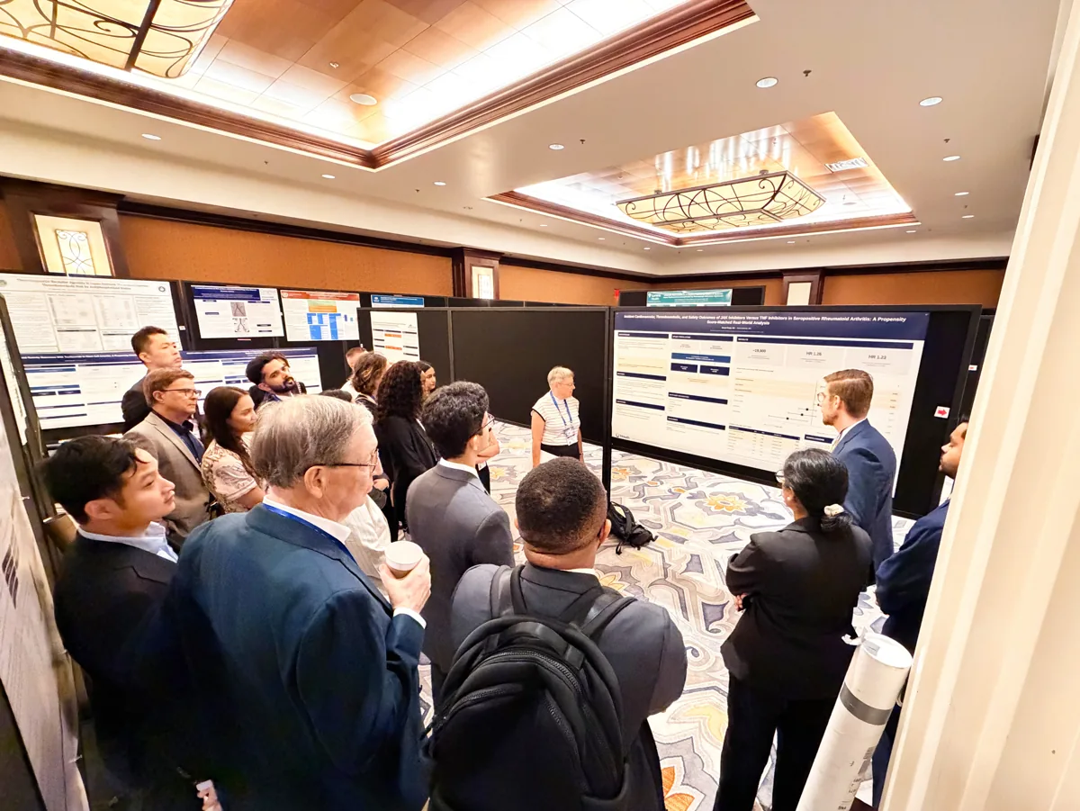 A presenter explaining a research poster to a gathered group.