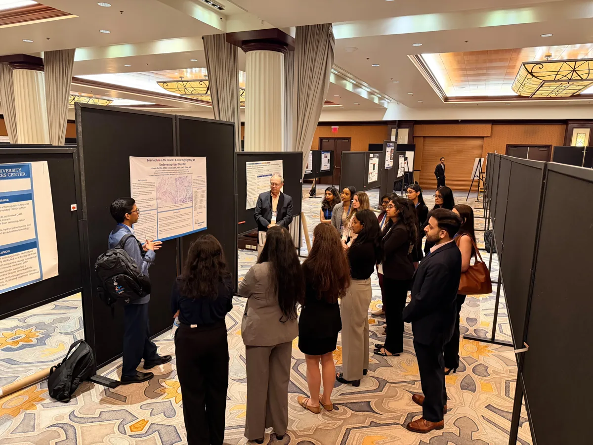 An investigator presenting a poster to faculty and peers.